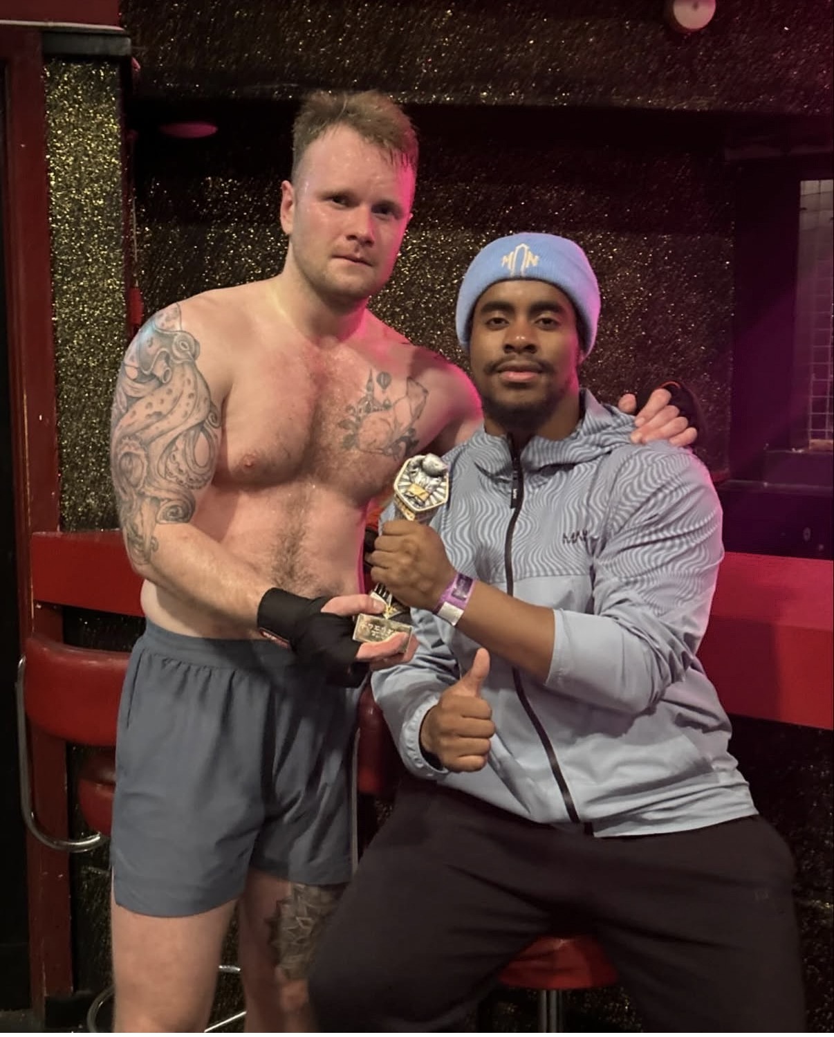 Fighter holding his trophy with Coach Leonardo