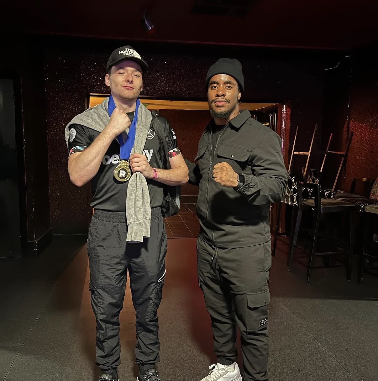 Fighter holding his medal alongside the coach